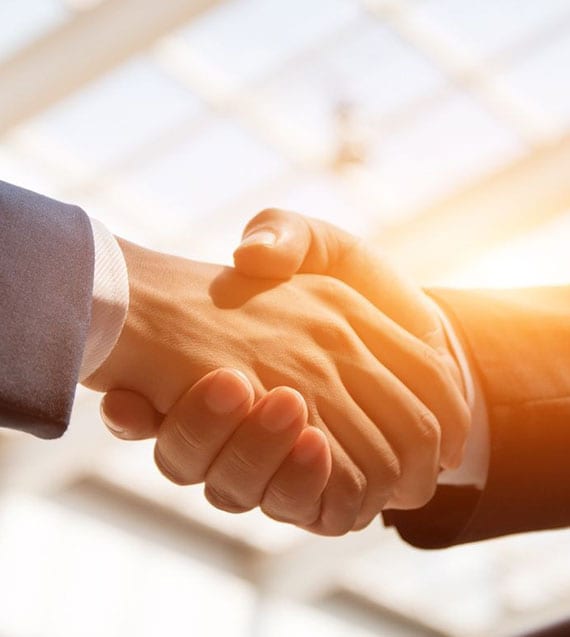 Two people shaking hands in a room with sunlight.